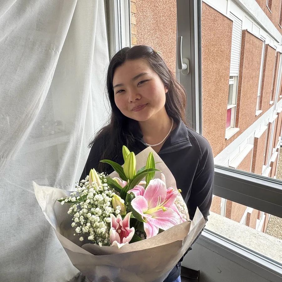 Jade Zhao by a window, holding pink lilies and baby's breath